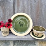 Dunkelgrüne Serie mit Grünten- und Gamsmotiv auf Becher, Teller und Schale mit Unterteller Geschirrserie in dunkelgrün bestehend aus Becher mit Grünten-Motiv, Teller und Schale mit Unterteller jeweils mit Gams-Motiv